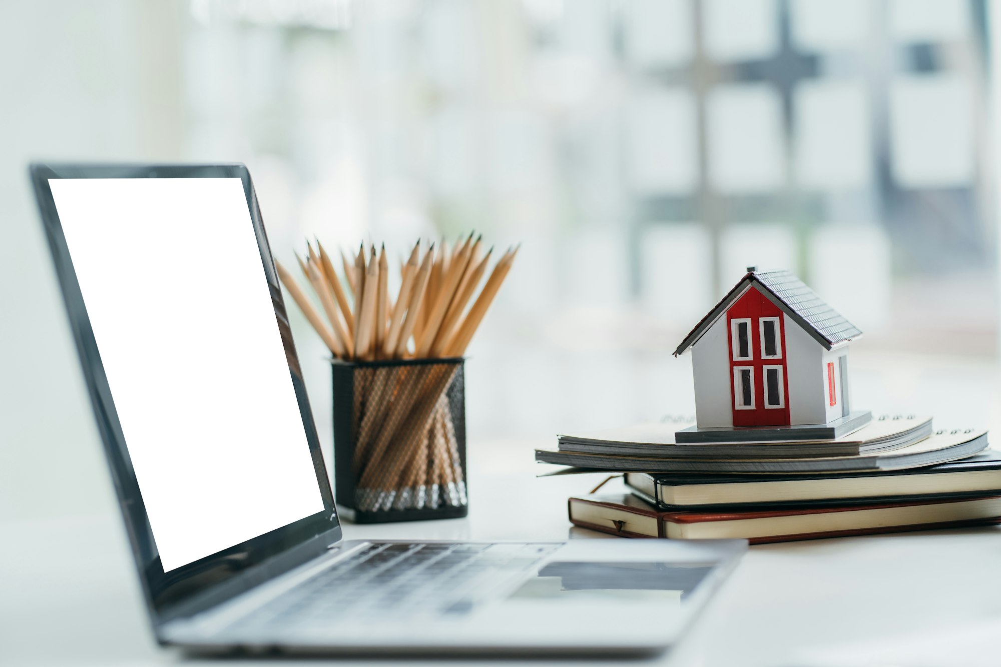 House model with laptop on table of real estate agent in office